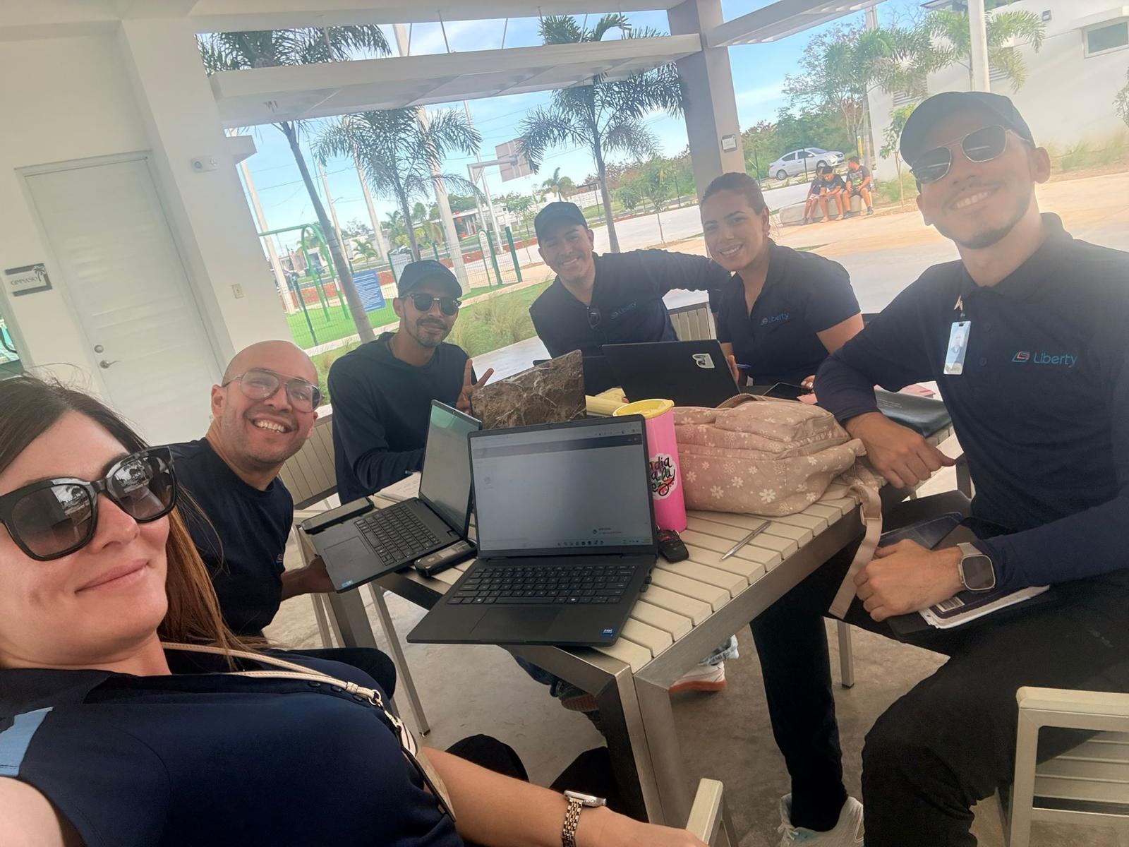 Team planning session around a laptop-covered table